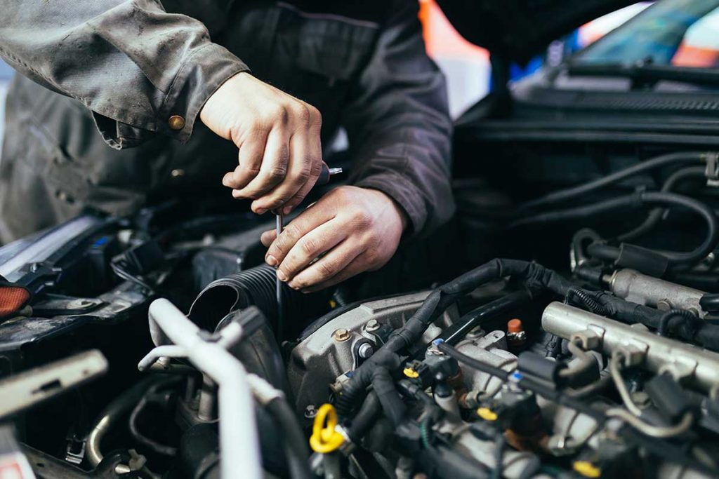 Mechanik při servisní kontrole motoru osobního automobilu