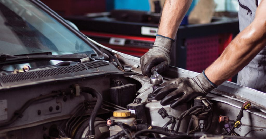 Práce na vozidle s otevřenou kapotou v dílně autoservisu